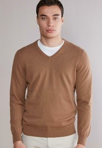 Brązowy sweter z dekoltem w serek, wykonany z miękkiej dzianiny, z długimi rękawami i dopasowanym krojem, o gładkiej fakturze i minimalnych detalach.