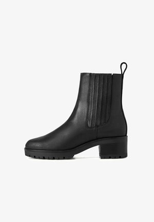 Musta nahkasaapas nilkkamittaisella varrella, jossa on elastiset sivupaneelit, vetoketju takana, paksu korko ja uritettua pohjaa tartuntaa varten.