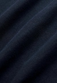 Námořnická modrá látka s jemnou strukturou, s horizontálním žebrováním a subtilním leskem, umístěná tak, aby ukázala hloubku a plynulost.
