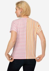 T-shirt a maniche corte a righe, con righe rosa e bianche da un lato e righe arancioni e bianche dall'altro, con scollatura rotonda.