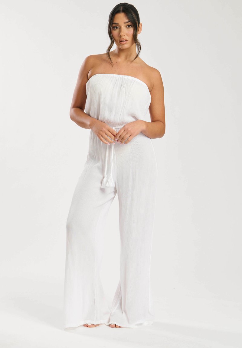 Mono blanco sin hombros con textura acanalada, diseño de pierna ancha y cinturilla elástica con cordón y borlas.