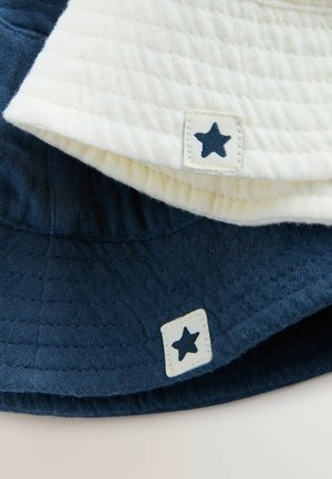 Zwei Bucket Hats, einer in Creme und einer in Marineblau, aus strukturiertem Stoff mit quadratischen Etiketten, die jeweils einen blauen Stern zeigen.