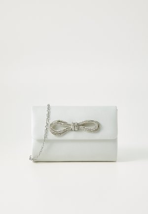 Pochette en simili cuir blanc avec une chaîne argentée et un accent de nœud décoratif orné de strass, présentant une texture lisse et une forme rectangulaire.