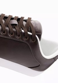 Sneaker in pelle marrone con accenti bianchi, punta rotonda, chiusura con lacci marroni e superficie testurizzata. Presenta una suola in gomma bianca.