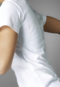 Valkoinen, istuva t-paita, joka on valmistettu puuvillasta. Siinä on lyhyet hihat ja sileä pinta, jolla on kevyt kiilto ilman näkyviä kuvioita.