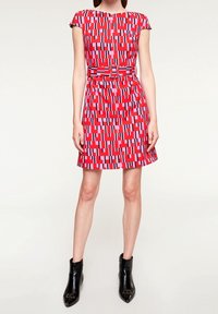 Red and pink patterned dress with short sleeves, belted waist, and A-line skirt. Worn with black ankle boots.