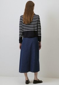 Gestreepte marineblauwe en witte lange mouw top gecombineerd met een donkere denim maxi rok, met een rechte snit en zijnaden, gedragen met zwarte instappers.