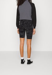 Svarta och grå mönstrade cykelshorts med midjehöjd, matchade med en svart och grå sweatshirt, bärs tillsammans med svarta högskor.