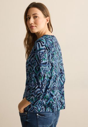Multikleurige langemouwtop met een blauw en groen abstract bloemmotief. Zacht stof, relaxte pasvorm en ronde halslijn.