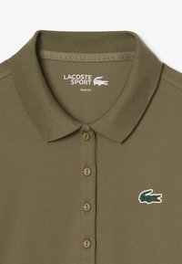 Polo slim-fit en verde oliva hecho de tela texturizada, con un cierre de tres botones y un pequeño logo bordado de cocodrilo.