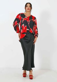 Rood en zwart bloemenblouse met balonsleeves, gecombineerd met een gladde zwarte satijnen rok en rode plateauhakken.