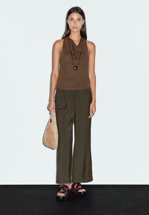 Brown cowl-neck knitted top, olive wide-leg pants, brown flat sandals, and a light brown bag. Simple and modern design with a relaxed fit.