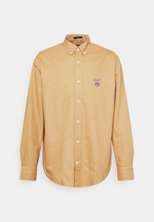 Light brown long-sleeve button-up shirt with a buttoned collar and GANT logo embroidered on the left chest.