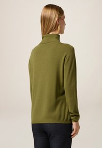 Maglione verde oliva con colletto alto e maniche lunghe, realizzato in un materiale morbido, con una vestibilità rilassata e spacchi laterali all'orlo.