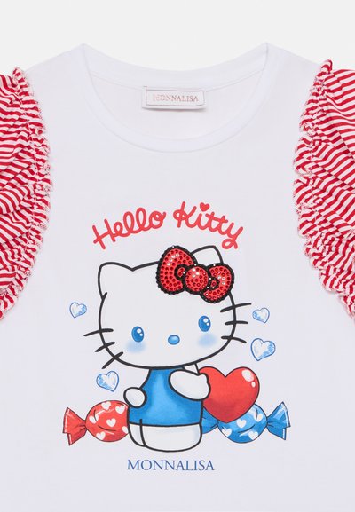 Λευκό μπλουζάκι με βολάν στις μανσέτες, κόκκινες και άσπρες ρίγες, πολύχρωμο γραφικό Hello Kitty με κόκκινο φιόγκο και μο τίβο καραμέλας. Ορατή ετικέτα του κατασκευαστή.