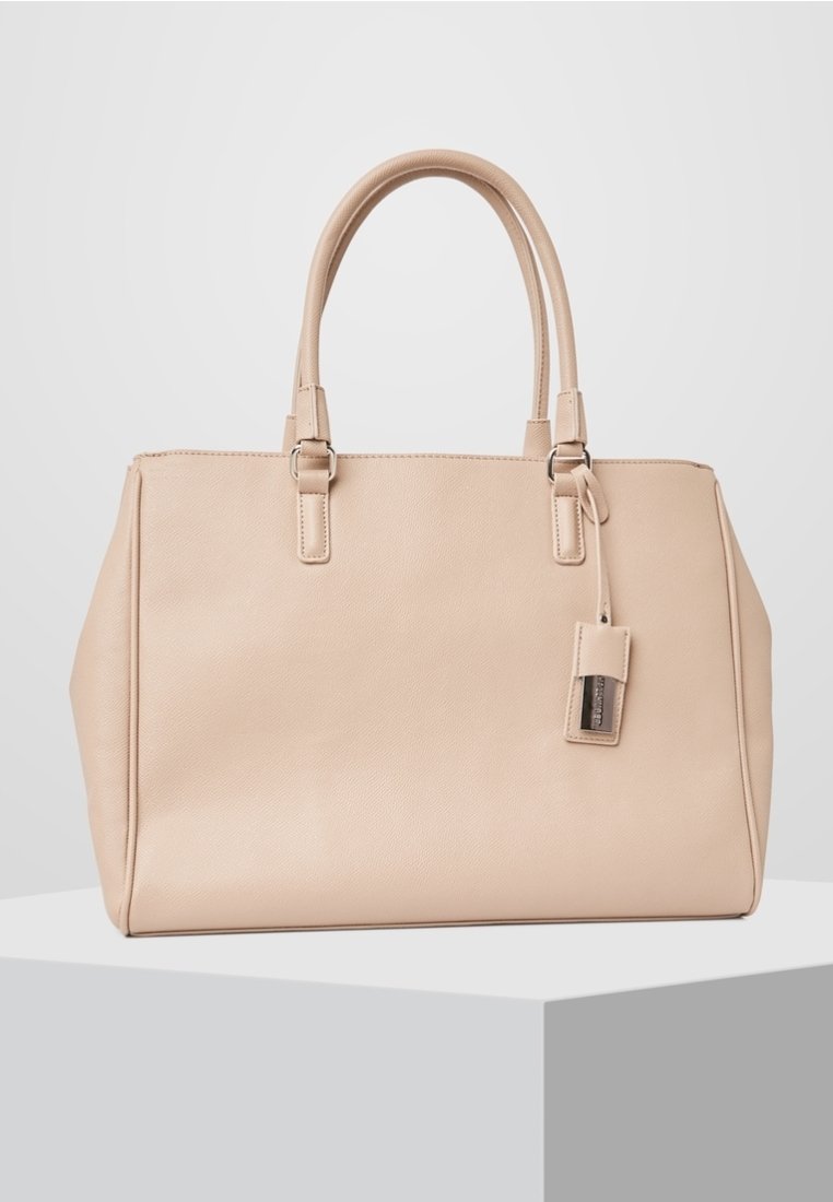 Borsa a mano in pelle beige con doppi manici, forma rettangolare, texture sottile e etichetta removibile. Presenta linee pulite e design strutturato.