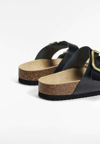 Zwarte leren sandalen met een kurken tussenzool en een textuur rubberen buitenzool. Kenmerkend zijn de gespsluiting en het open achterontwerp voor eenvoudig aan- en uittrekken.