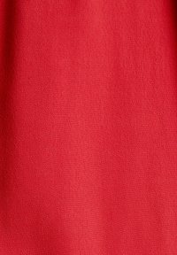 Tissu rouge avec un motif fin et texturé, doté de douces plis, uniformément éclairé avec des ombres subtiles.