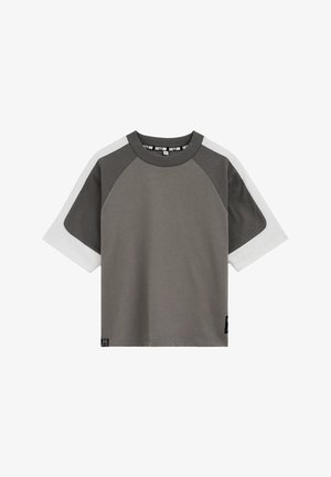 Koszulka raglanowa z krótkim rękawem, ciemnoszara na tułowiu i rękawach, z białymi panelami rozciągającymi się od górnej części ramion do końców rękawów.