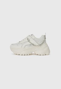 Chunky white sneakers with mixed material upper, silver accents, prominent sole, and a chain detail on the side.