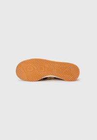 Sål med orange gummistøtte, der har det prægede ord "ZARA" i et zigzag-mønster på en hvid baggrund.