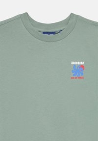 Grüne Baumwoll-T-Shirt mit rundem Ausschnitt und kurzen Ärmeln. Verfügt über eine mehrfarbige Grafik auf der Brust mit dem Text "Ericeira, Sol de Verão."