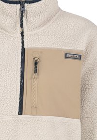 Fleece-Pullover in Creme mit einer beigen Brusttasche. Mit einem halben Reißverschluss, einer Reißverschluss-Tasche und strukturiertem Material. Sublevel-Branding vorhanden.