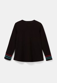 Czarna koszula z długim rękawem z trójkątnym haftem w kolorze czerwonym i niebieskim na mankietach. Miękka tkanina z okrągłym dekoltem i zaokrąglonym dołem.