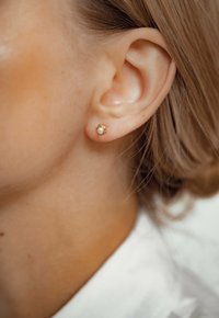 Gouden studs met een kleine witte parel, gezet in een delicate, afgeronde zetting met een gladde afwerking.