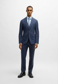 Navy blue suit with a tailored design, textured fabric, single-breasted jacket, matching trousers, and a light blue striped tie. Black dress shoes.