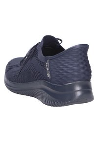 Zapatillas sin cordones de color azul marino con parte superior de malla texturizada, cordones elásticos y suela acolchada con un patrón acanalado para mayor tracción.