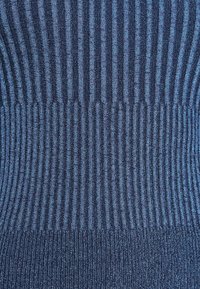 Sweter na drutach w ciemnoniebieskim, prążkowanym wzorze z różnymi szerokościami pasków, gładką strukturą i delikatnym połyskiem. Brak widocznych elementów metalowych lub akcentów.