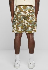 Cargo-shorts i camouflagemønster med nuancer af grøn, brun og creme. Har sidelommer og en afslappet pasform, lavet af letvægtsstof.