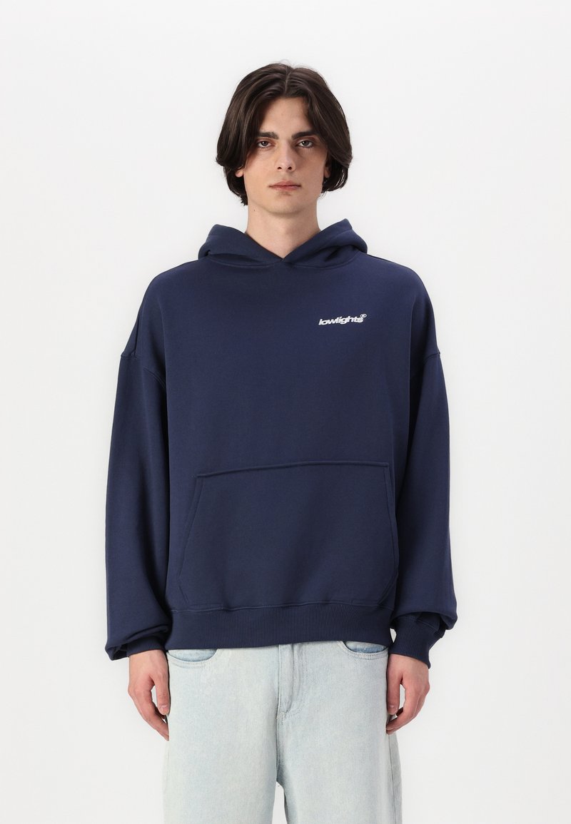 Felpa con cappuccio blu navy, vestibilità rilassata, realizzata in tessuto morbido. Presenta una tasca frontale e un logo bianco sul petto. Polsini e orlo a coste.
