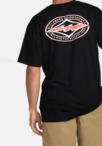 Sort bomulds t-shirt med et grafisk logo på ryggen i rød og hvid, med korte ærmer og rund halsudskæring.