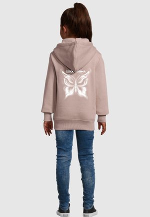 Light pink hoodie with a back print featuring a white butterfly and the text "COOL KARMA." Paired with blue denim jeans and black sneakers.