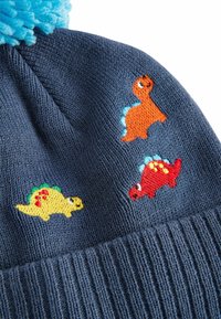Gebreide marineblauwe muts met kleurrijke dinosaurus borduurwerk: oranje, rode en gele dinosaurussen met blauwe accenten, afgewerkt met een blauwe pompon.