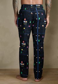 Fekete pizsama nadrág Pac-Man mintával, színes karakterekkel, fákkal és labirintus mintákkal. Puha anyagból készült, rugalmas derékpánttal.