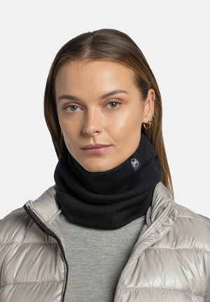 Black knitted neck warmer with a ribbed texture and a small logo tag; worn with a light gray top and a shiny silver puffer jacket.