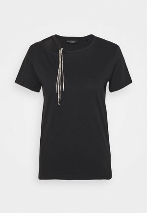 T-shirt noir à manches courtes avec un col rond et un détail de chaîne en strass argentés suspendue près de l'épaule gauche.