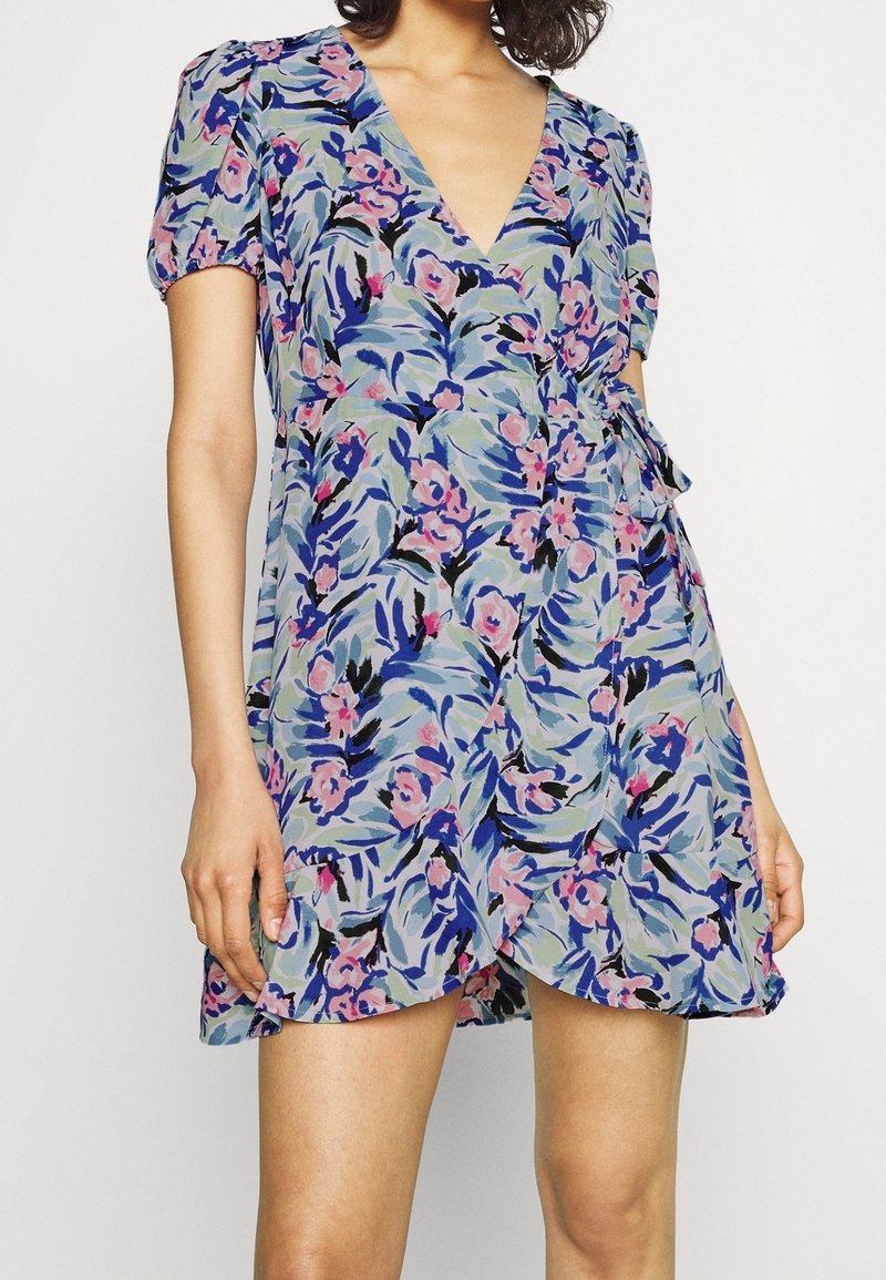 Robe courte portefeuille à fleurs avec manches bouffantes, encolure en V et lien latéral dans une palette de couleurs pastel bleu, rose et marine.