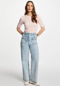 Top corto a maniche corte a righe rosa chiaro abbinato a jeans a gamba larga azzurri a vita alta, con tasche anteriori e vestibilità comoda.