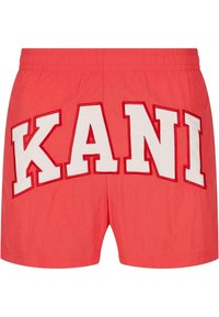 Red shorts featuring large white embroidered letters spelling "KANI" on the back. Elastic waistband with a smooth texture.