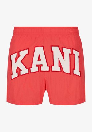 Rode shorts met grote witte geborduurde letters die "KANI" op de achterkant spellen. Elastische tailleband met een gladde textuur.