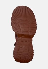 Brun gummisul med texturerat mönster, med spårade linjer som strålar ut från mitten, präglad "CAMPPER" och skostorlek 38.