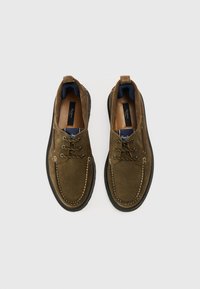 Braune Wildleder-Schnürschuhe mit kontrastierenden weißen Nähten, Gummisohlen und einer dunkelblauen Innensohle. Mit Metallösen und einer Lasche zum Anziehen ausgestattet.