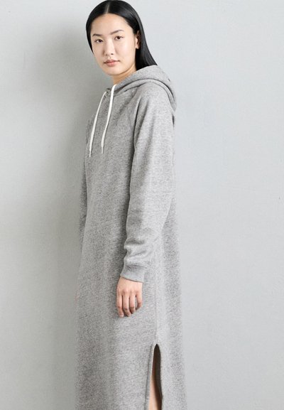 Grijze, lange hoodie jurk met een split aan de voorkant, gemaakt van zachte stof. Beschikt over verstelbare trekkoorden en ribgebreide manchetten.