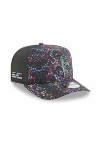 Casquette noire avec un motif de éclaboussures colorées, logo en fleur-de-lis brodé en argent et or, et une étiquette tissée indiquant "Crucial Catch".