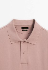 Polo rose pâle en tissu texturé. Il présente un col classique et une patte à deux boutons. L'étiquette indique "Massimo Dutti, Fabriqué en Turquie."