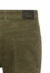 Olivgrüne Cordhosen verfügen über eine Gesäßtasche mit dekorativem Stich und einem schwarzen Etikett mit dem "camel active"-Logo.